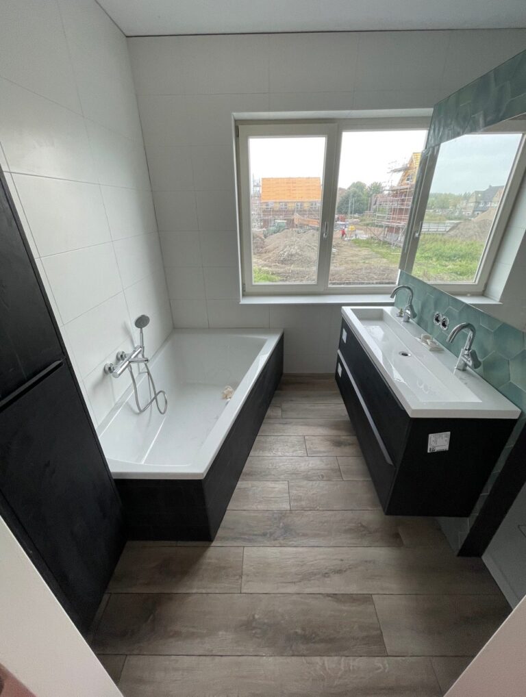 Badkamer in Boskoop met ligbad, wastafelmeubel en vloertegels in houtlook