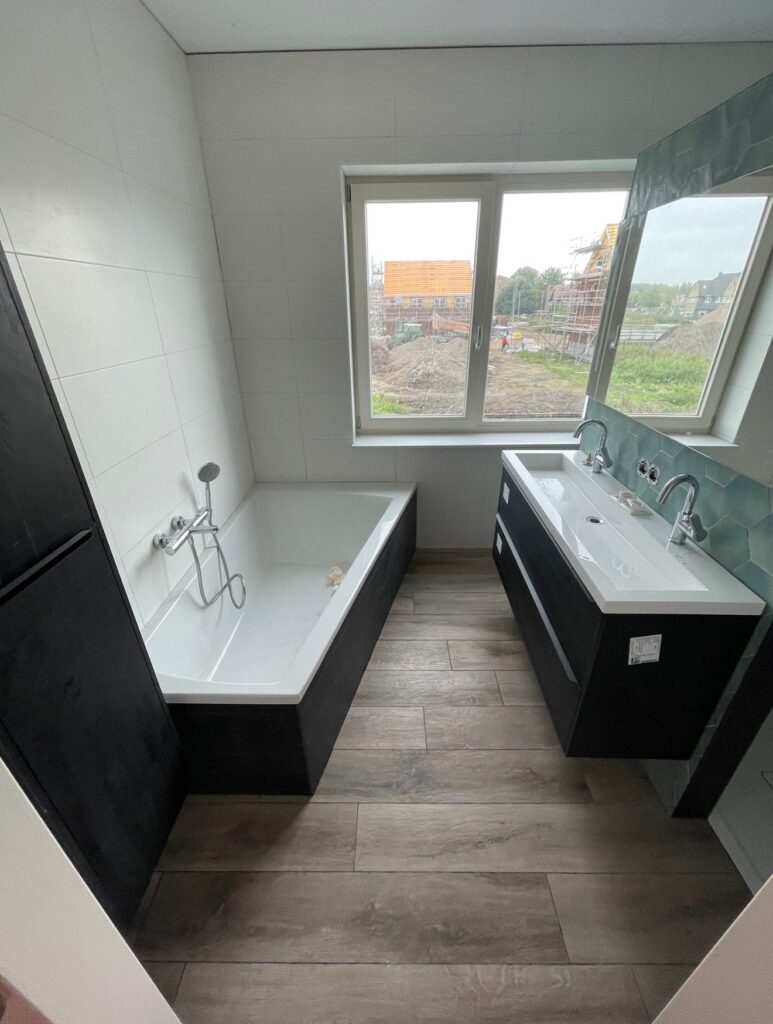 Badkamer in Boskoop met ligbad, wastafelmeubel en vloertegels in houtlook