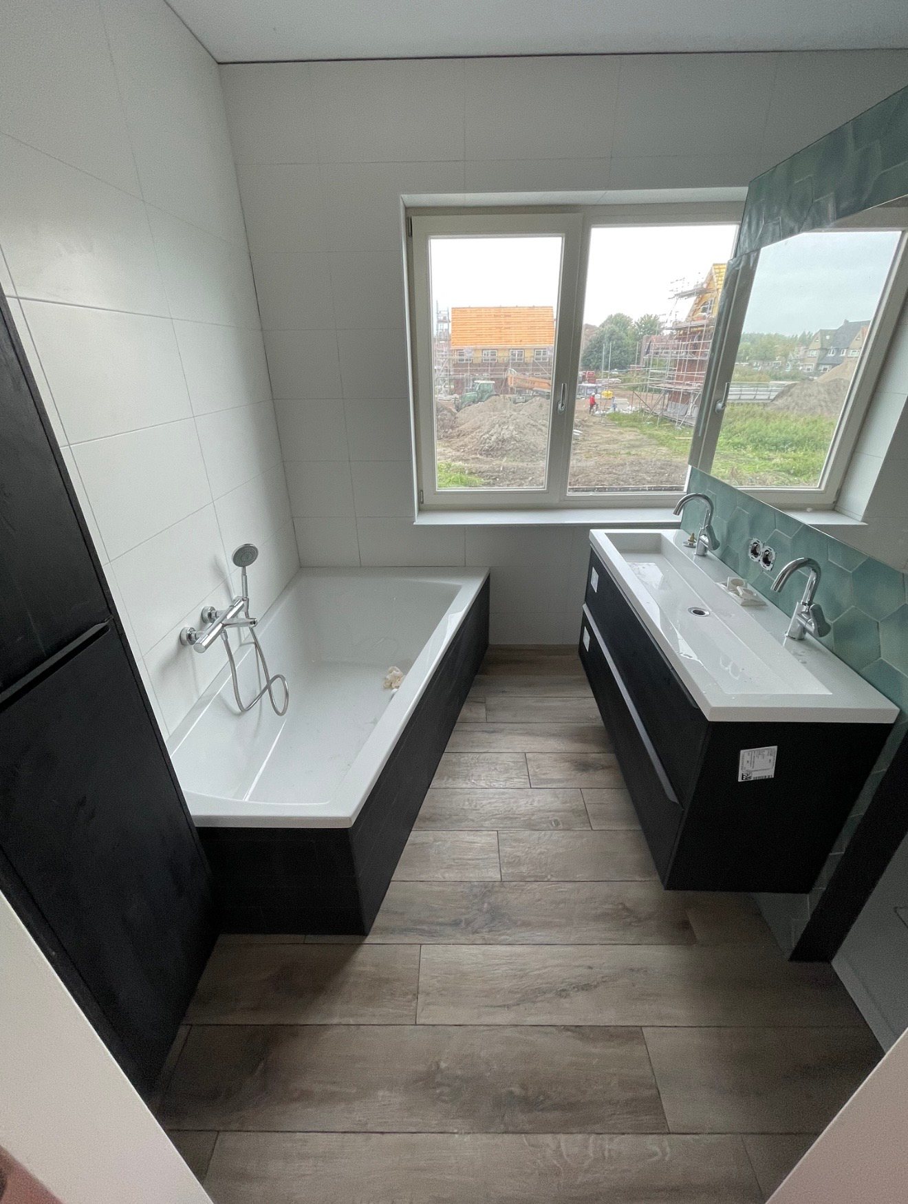 Badkamer in Boskoop met ligbad, wastafelmeubel en vloertegels in houtlook