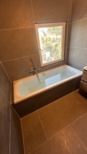 Nieuwe badkamer met ligbad en donkergrijze tegels in een voormalige slaapkamer