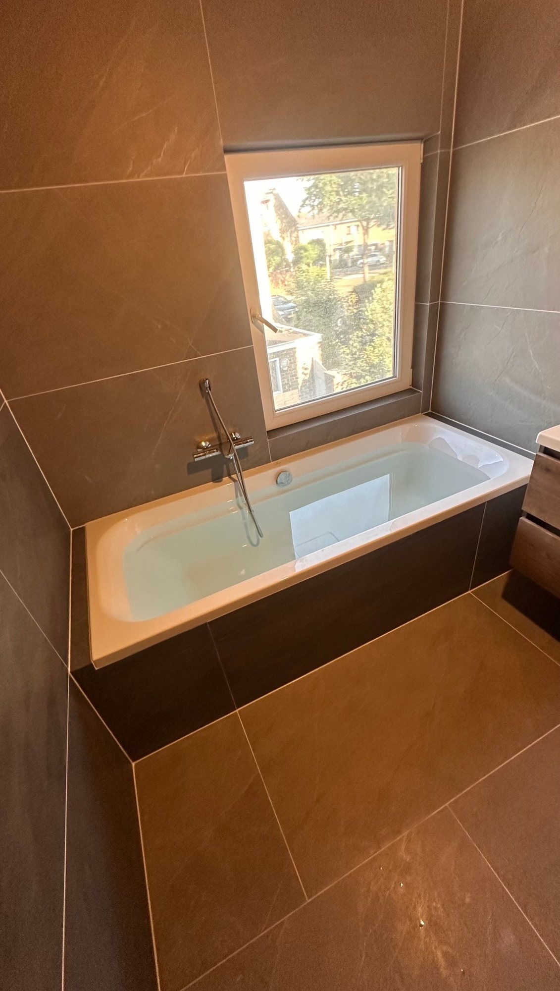 Nieuwe badkamer met ligbad en donkergrijze tegels in een voormalige slaapkamer